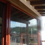 Custom painted and made Mahogany brown/brick retractable screen doors installed on the outside of the front view bi-folding doors for quick ventilation